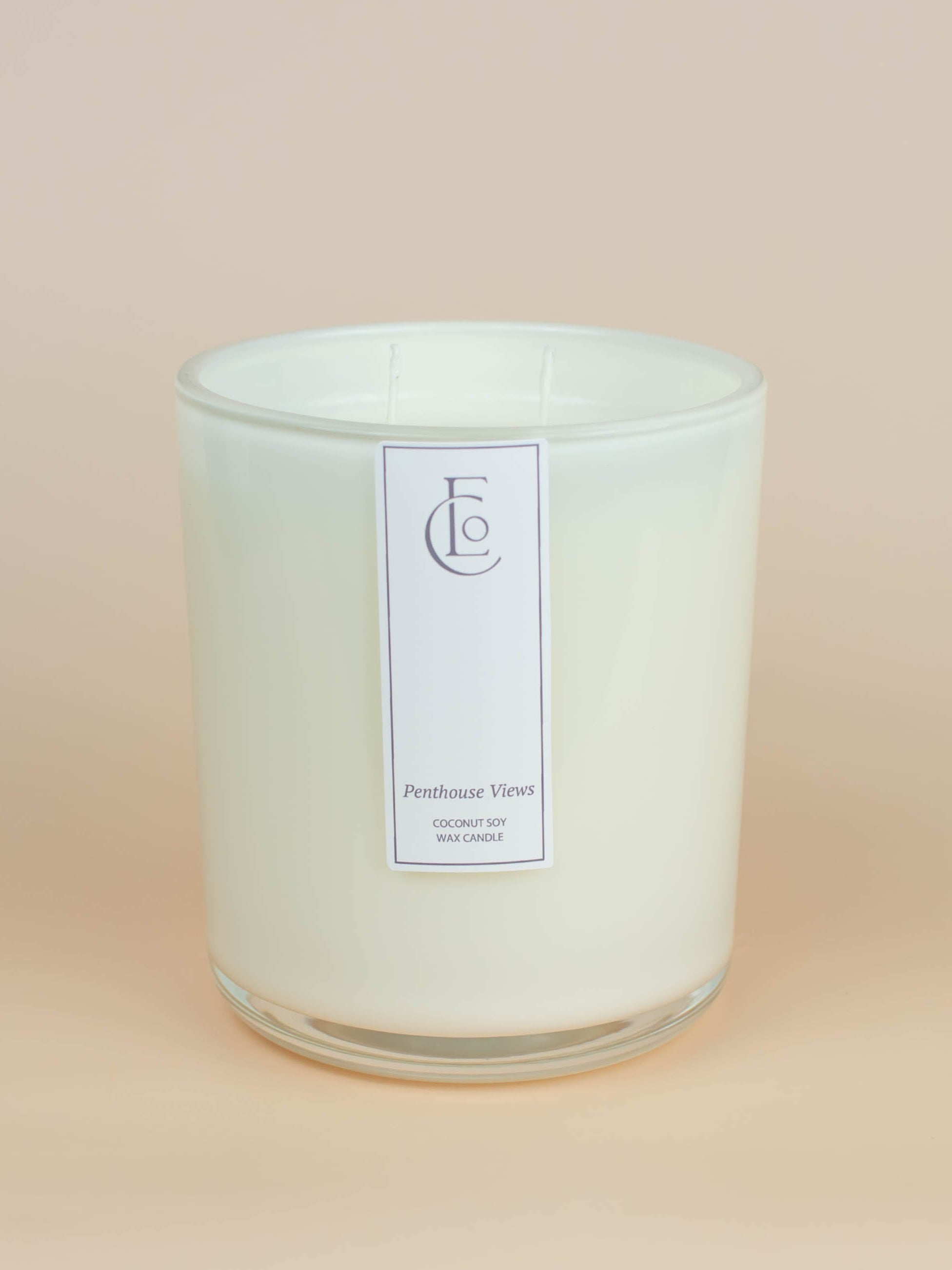 Glass candle jar with a cream label on a beige background